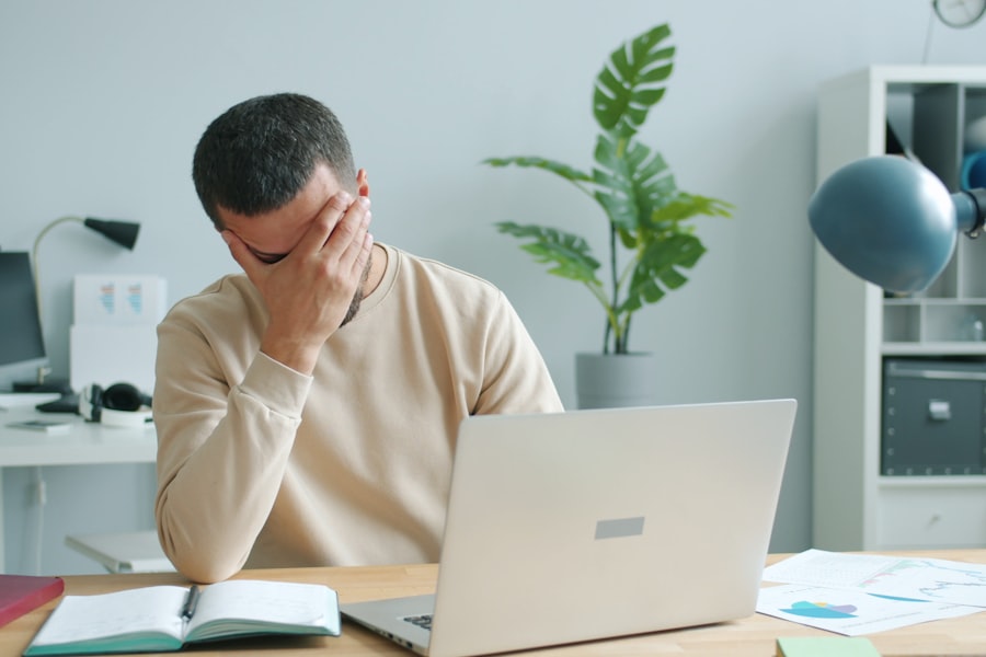 Frustrated business owner with head in hand in front of a laptop